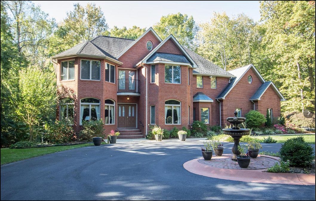 A large brick estate home with a fountain and circular drive
