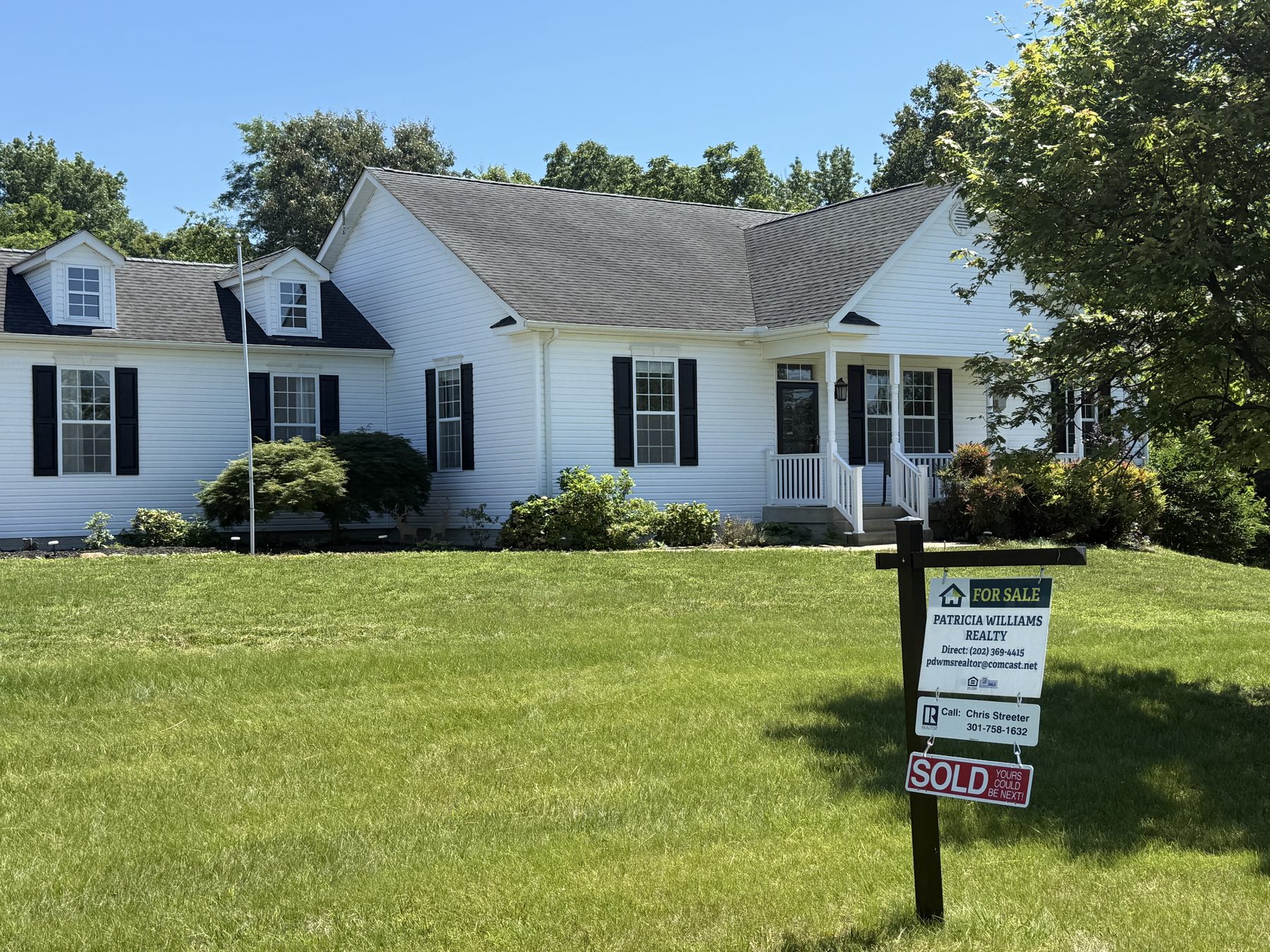 A white Cape Cod–style home with a PWR sold sign on the lawn
