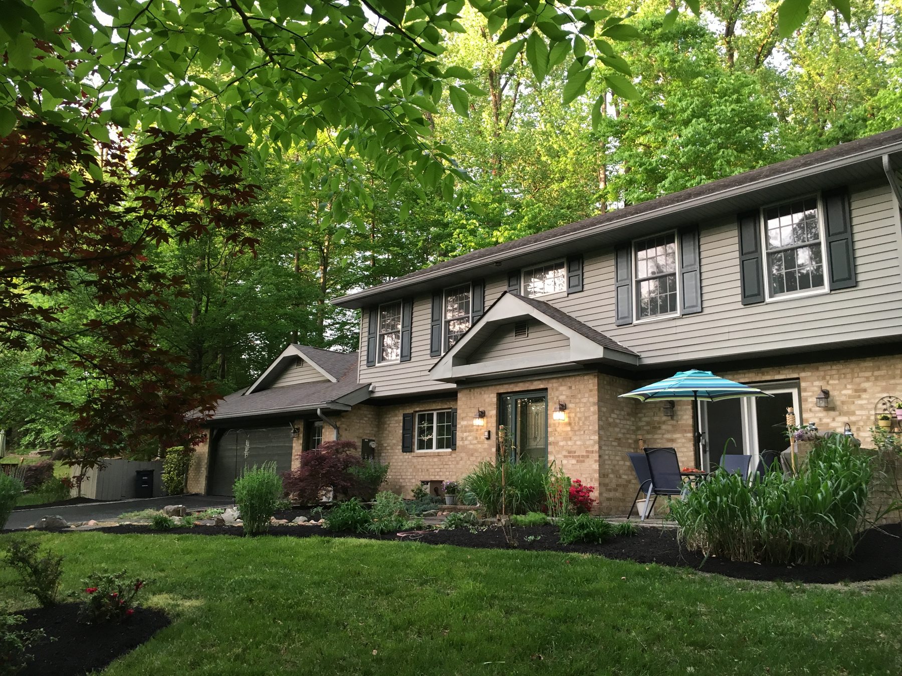 A two-story home set among mature trees with a landscaped front yard